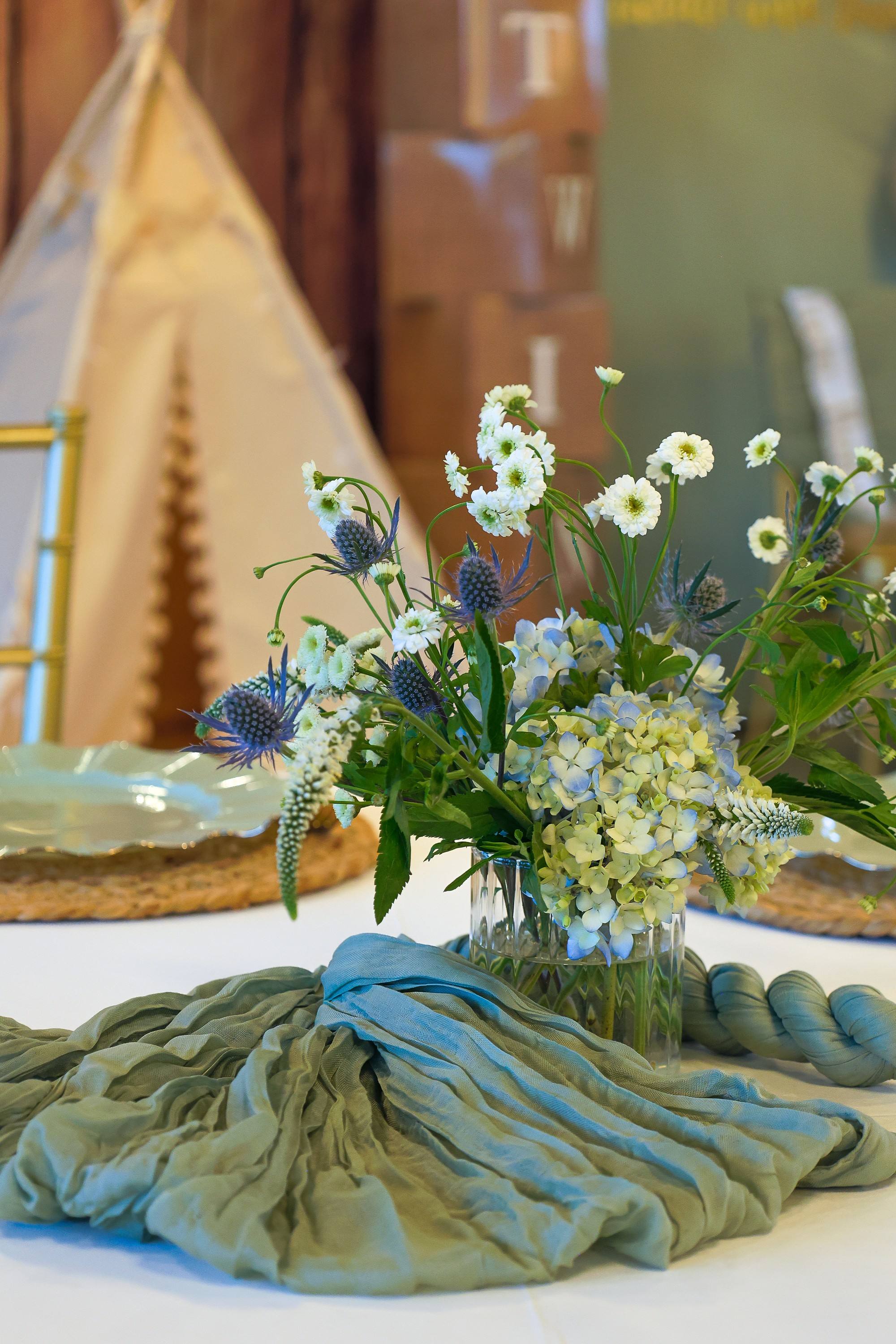 Baby shower floral centerpiece on a sage gauze table runner