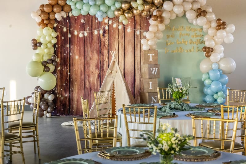 Rustic woodland backdrop and gold Chiavari chairs at a baby shower