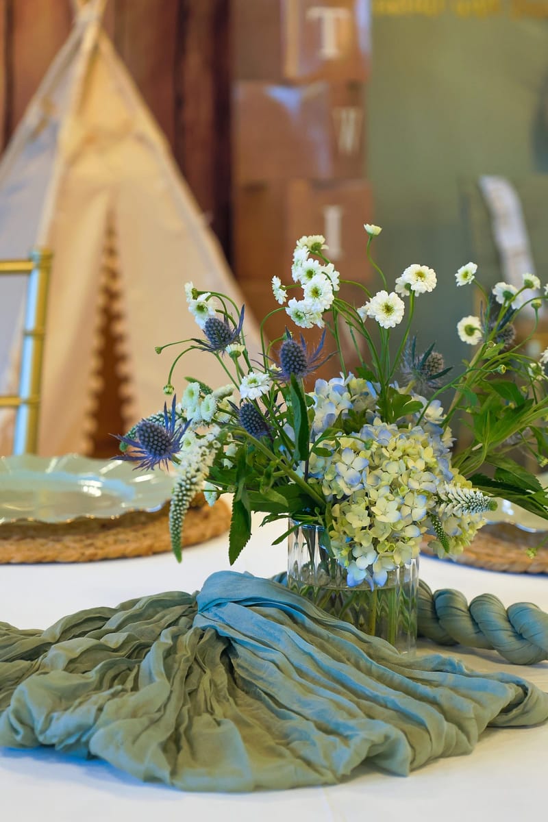 Baby shower floral centerpiece on a sage gauze table runner